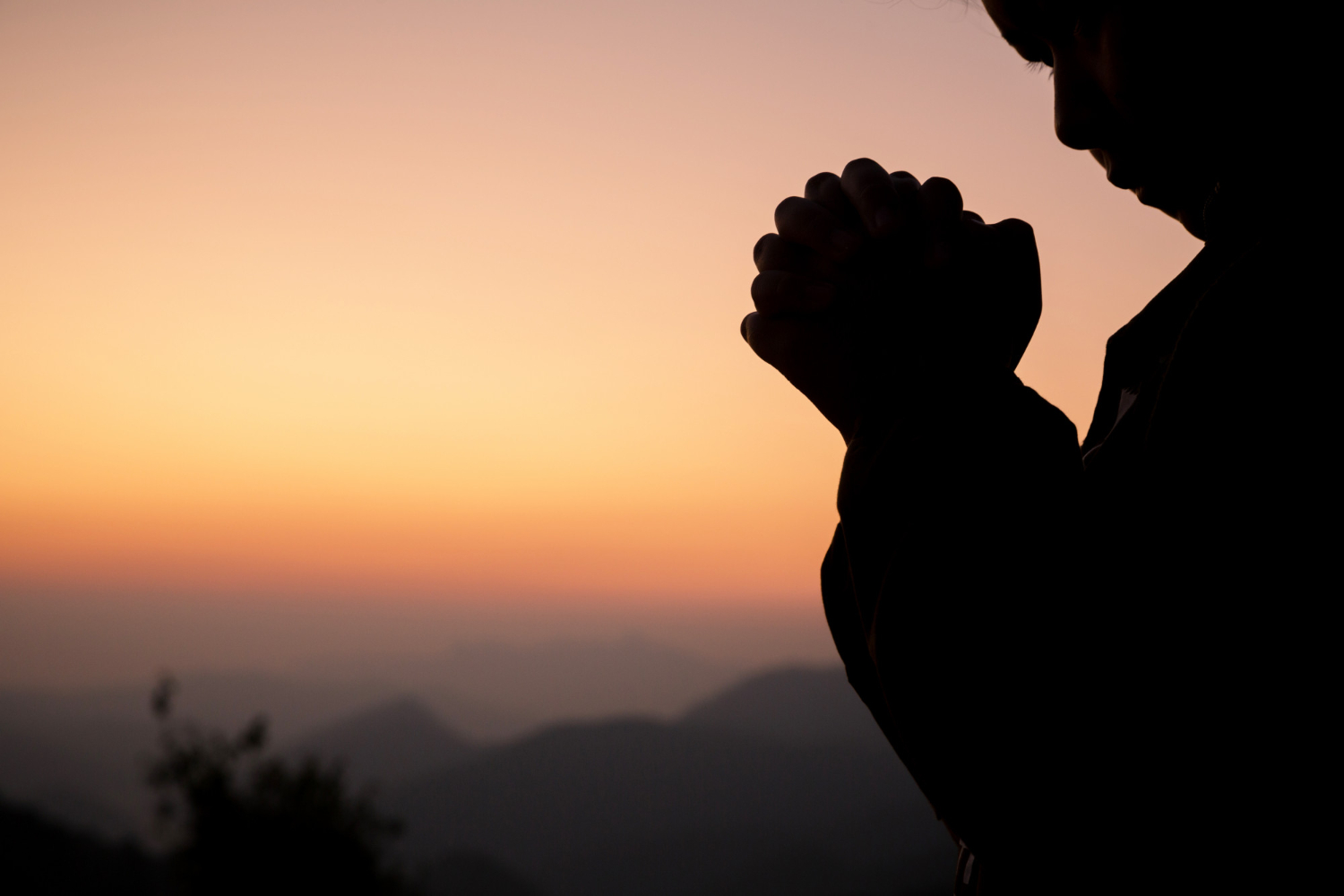 A girl is praying in the sunset background.