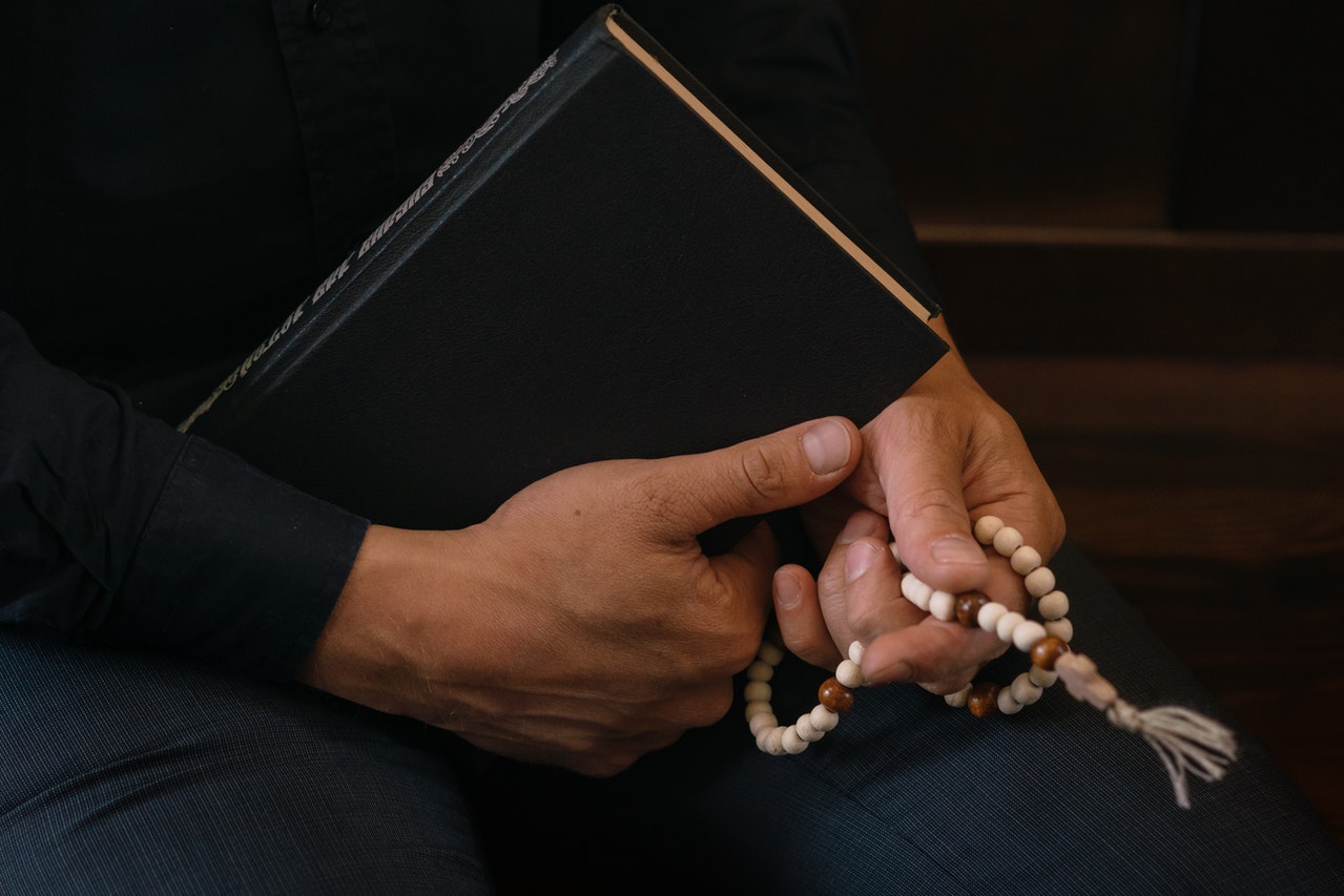 A Person Holding a Bible and a Rosary