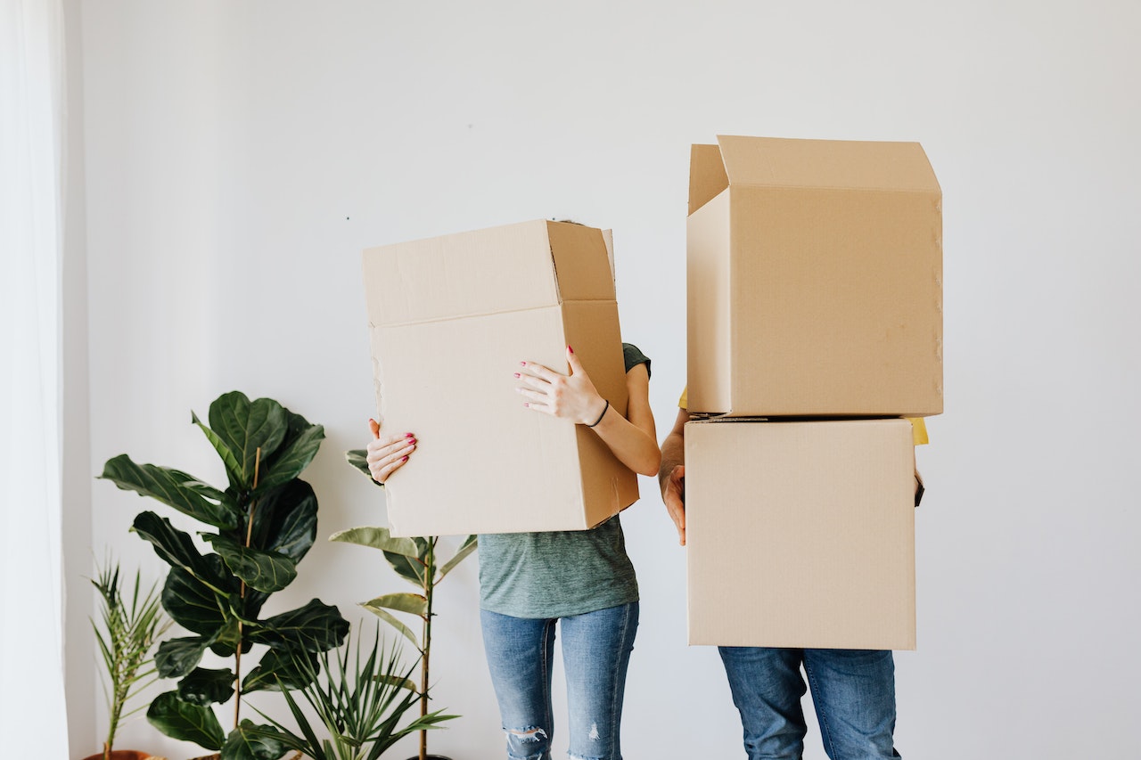 Couple carrying boxes in the living room as they move in their new house