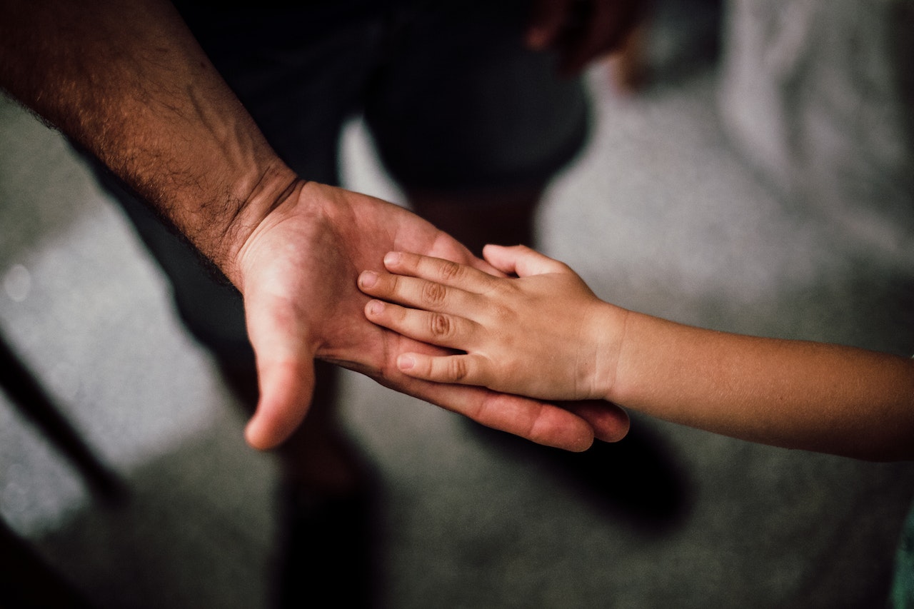 A child's hand on top of his dad's hand