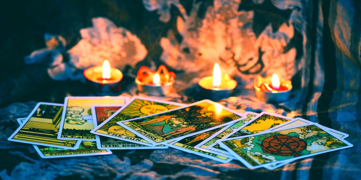 Different tarot cards scattered on each other with four lit candles close to them