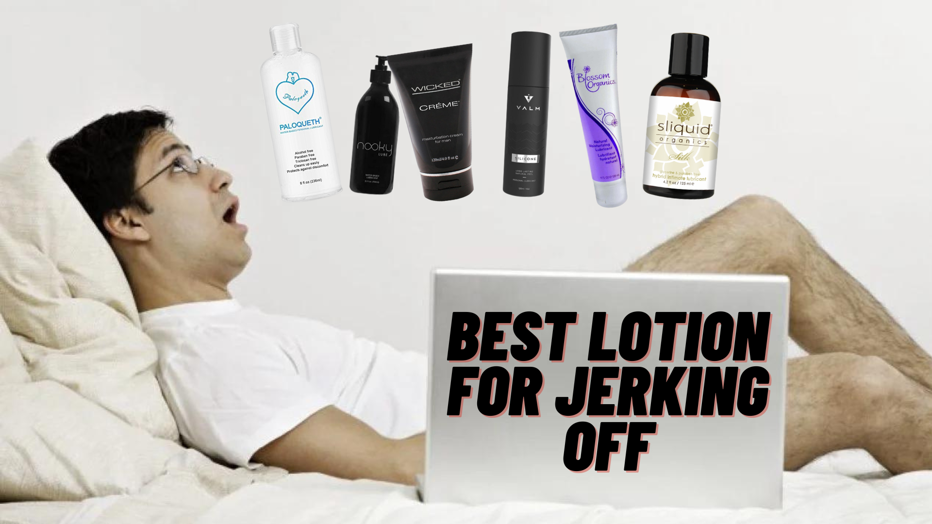 A man lying on the bed while masturbating with a laptop beside him and some lotion brands on top