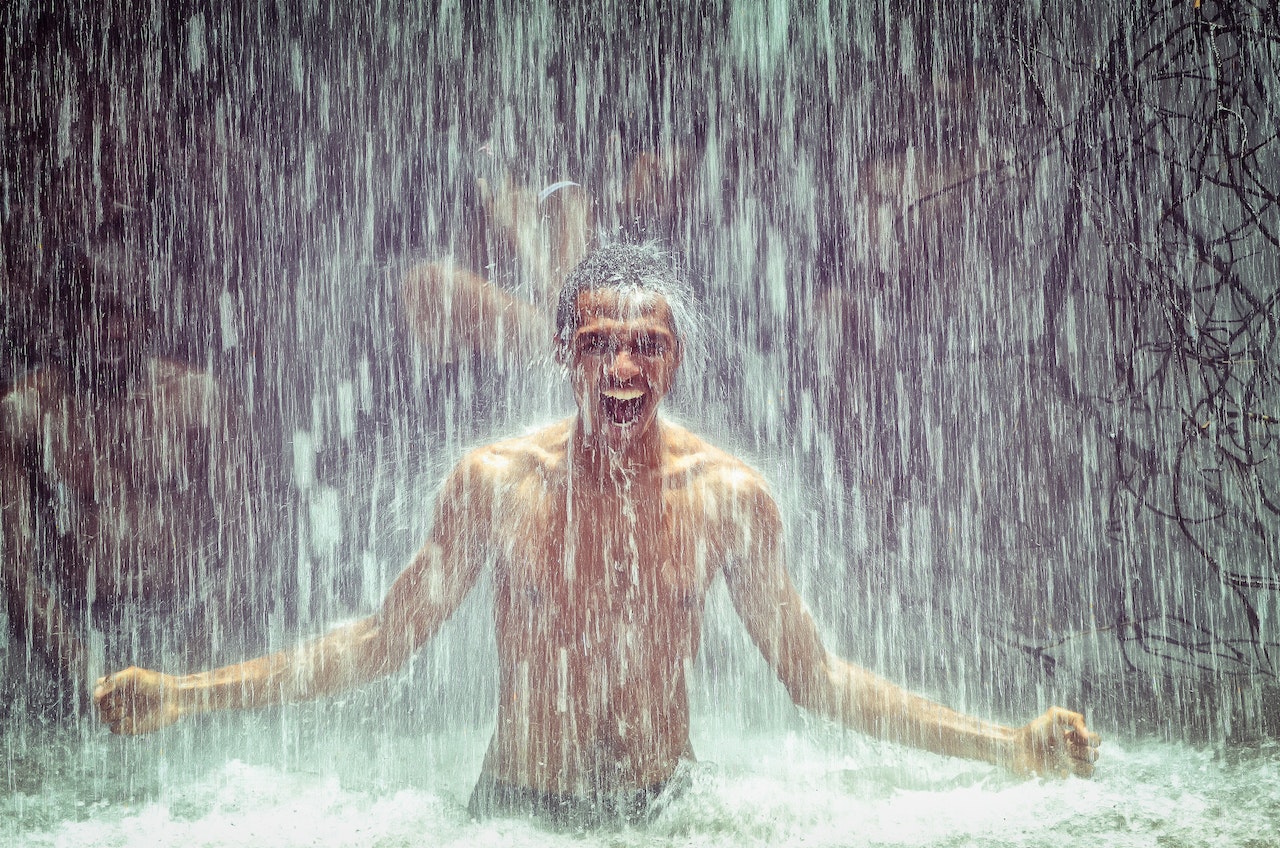 A Topless Man Under Water Falls