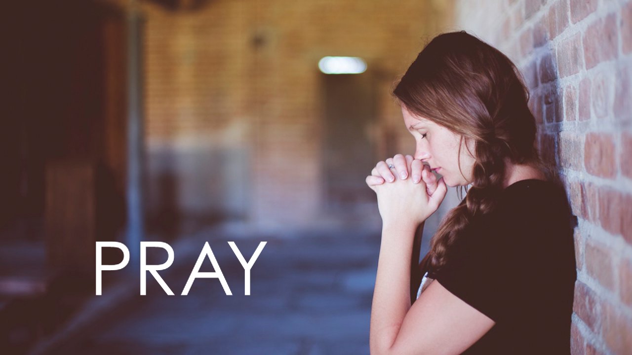 A young girl praying with her eyes closed and hands joined