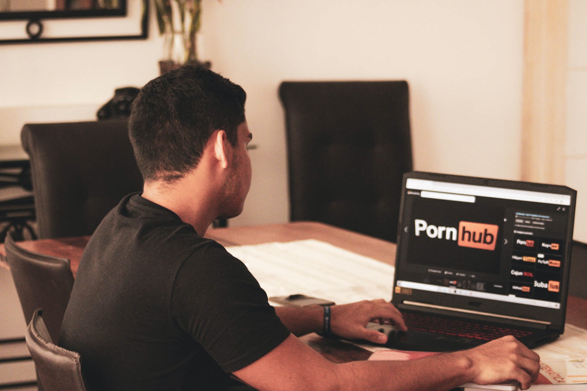 A man in black shirt is watching pornhub website on laptop