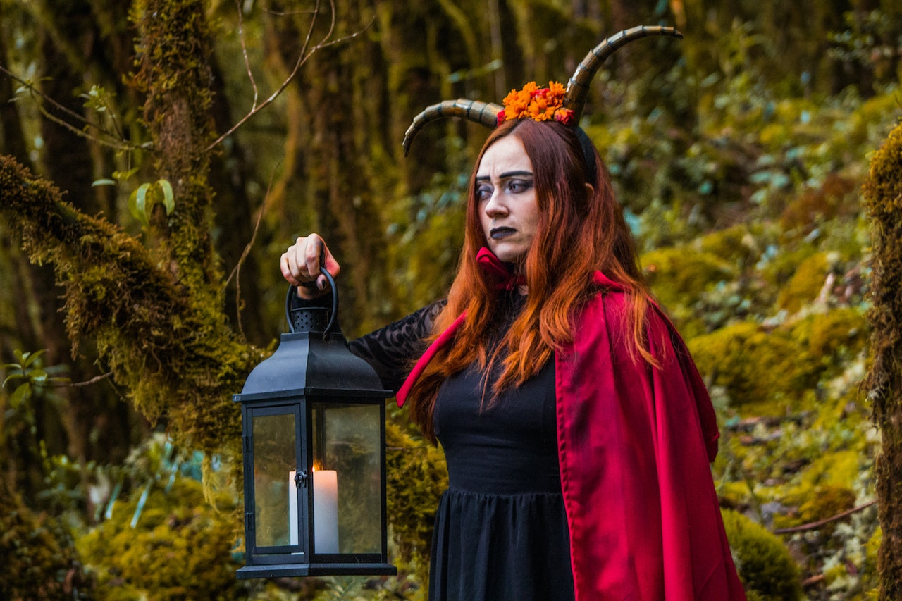 A Woman In Devil Costume Holding A Lamp