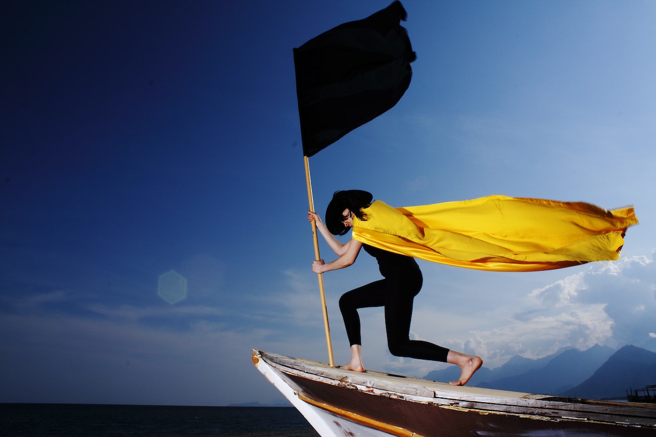 A Woman Holding A Black Flag At The Edge Of The Boat