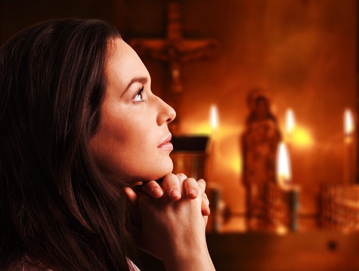 A girl sits in a church with her chin on her hands while candles are in the background