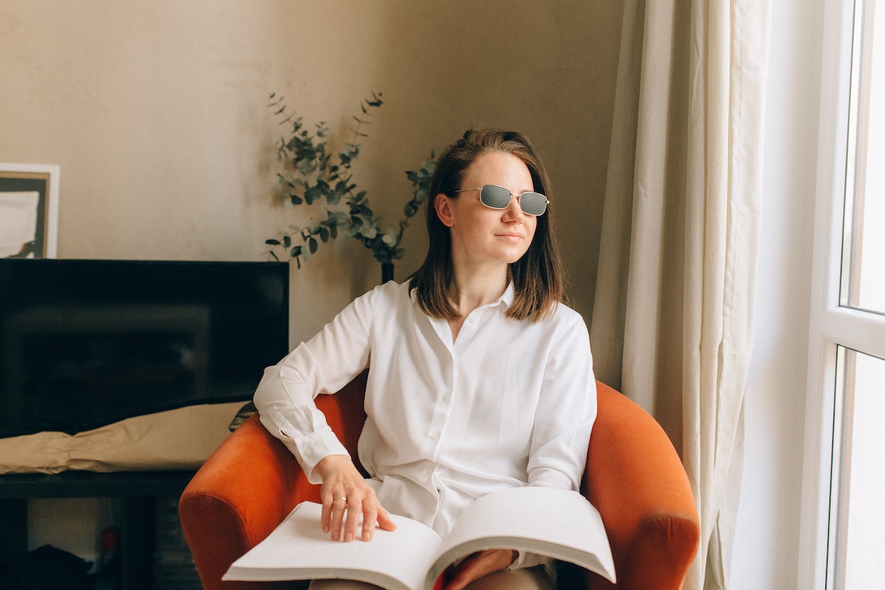 A Woman wearing Sunglasses while Reading Braille Book