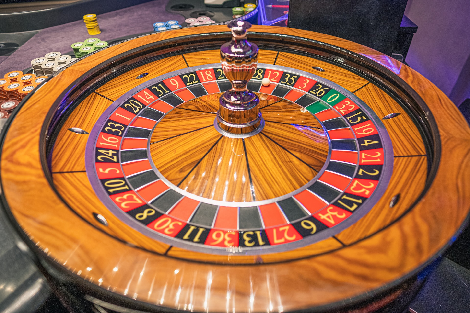A wooden roulette table with lots of casino chips beside it