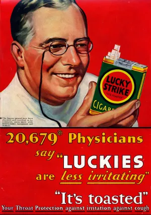 A doctor with reading glasses smiling while holding a box of cigarettes