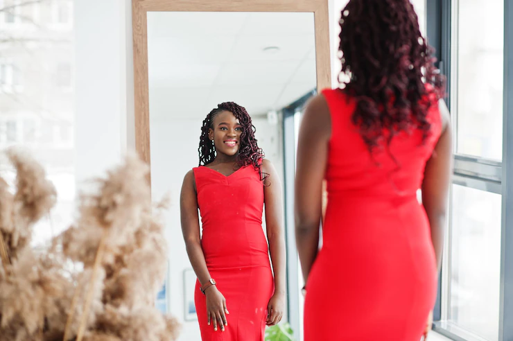 A woman in red dress is watching herself in mirror