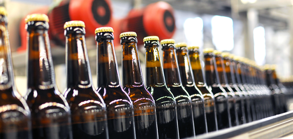 Brown filled bottles of beer all lined up on a machine