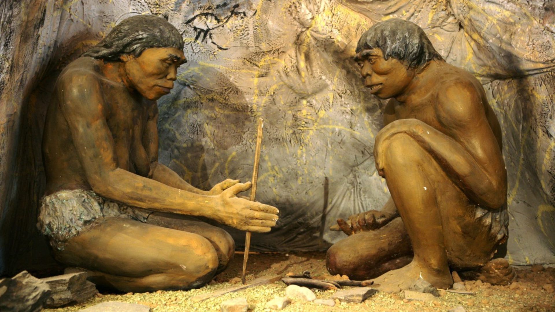 Two cavemen trying to make a fire