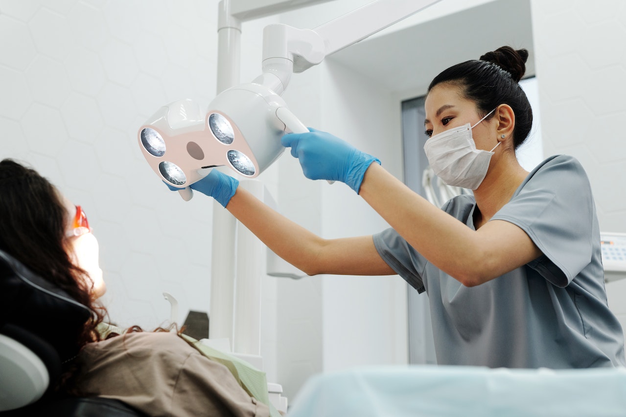 A dentist checking the teeth of the patient while fixing the light