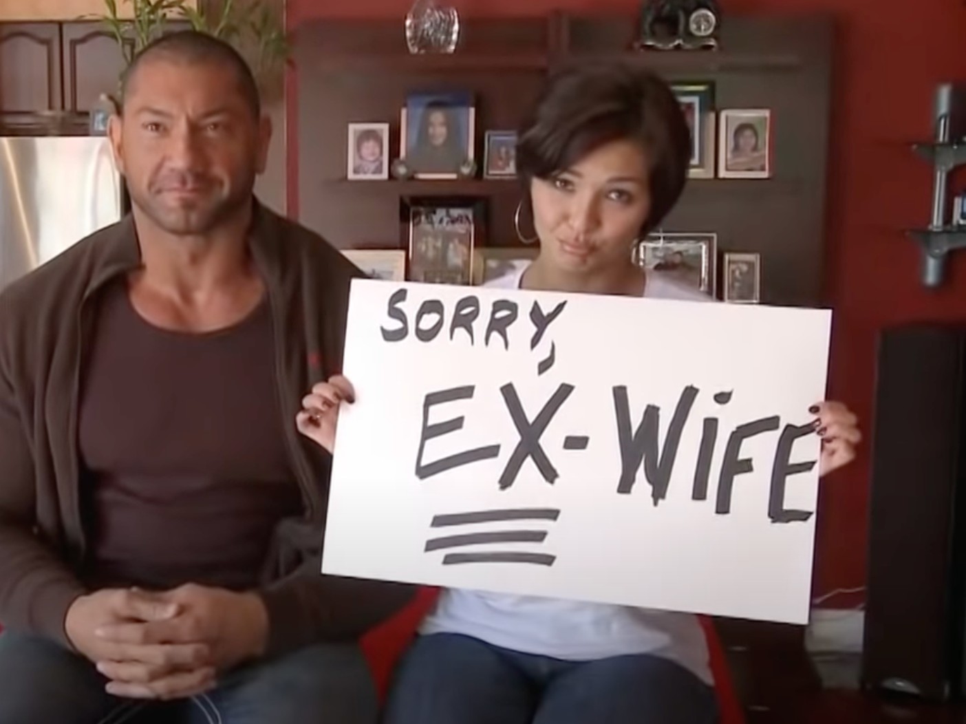 Glenda Bautista and her ex-husband Dave Bautista with Glenda holding a white sheet that says "sorry, ex-wife"