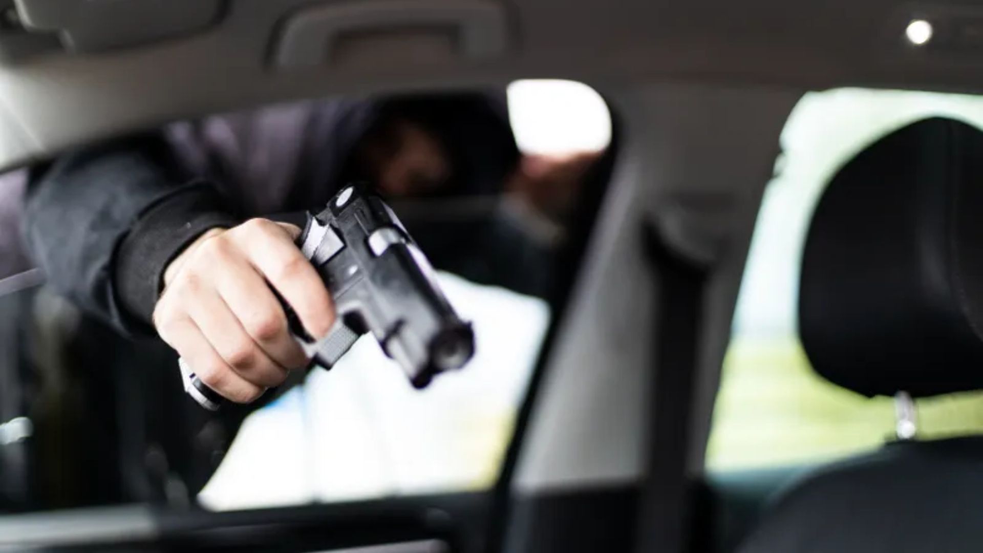 Person Peeking Inside Car With Pistol In Hand