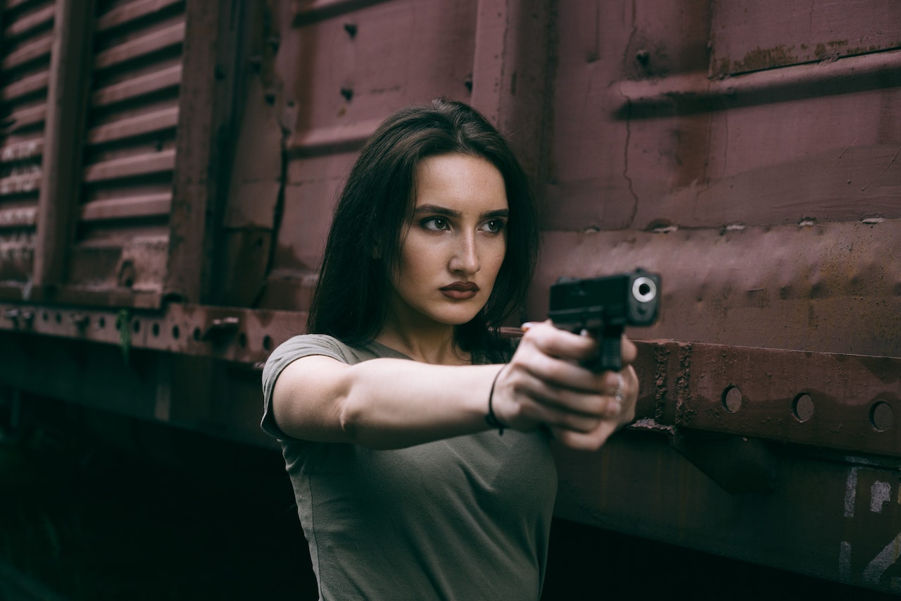 Woman in Gray Shirt Pointing a Gun