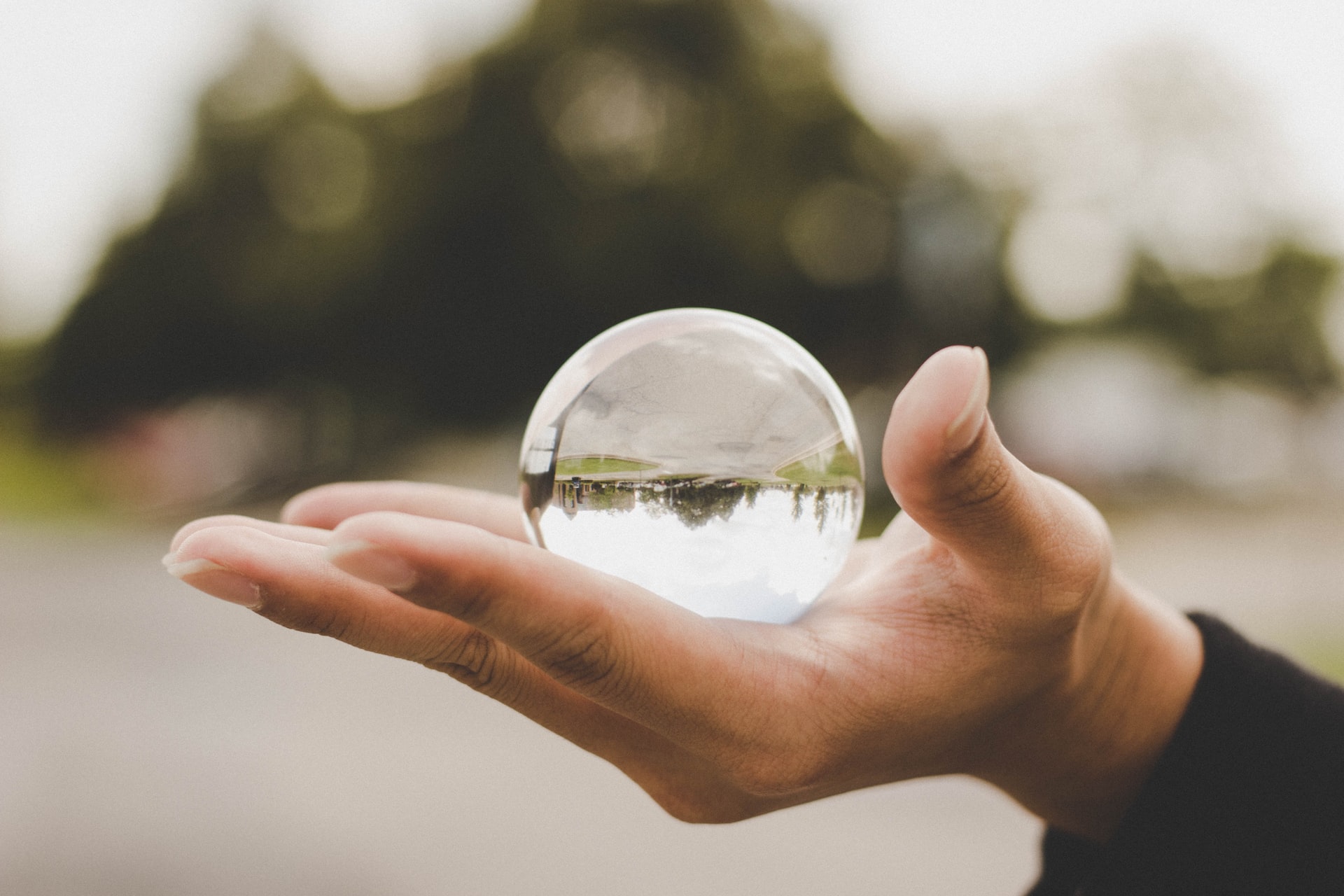 A person holding a small white transparent crystal ball on their palm