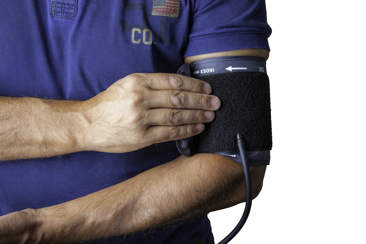 A man wearing a blue t-shirt with a blood pressure monitor on his arm