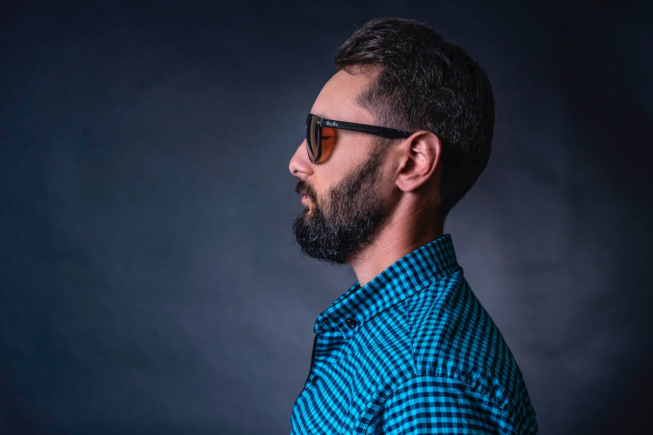 Man Wearing Checkered Shirt and sunglasses with left ear visible