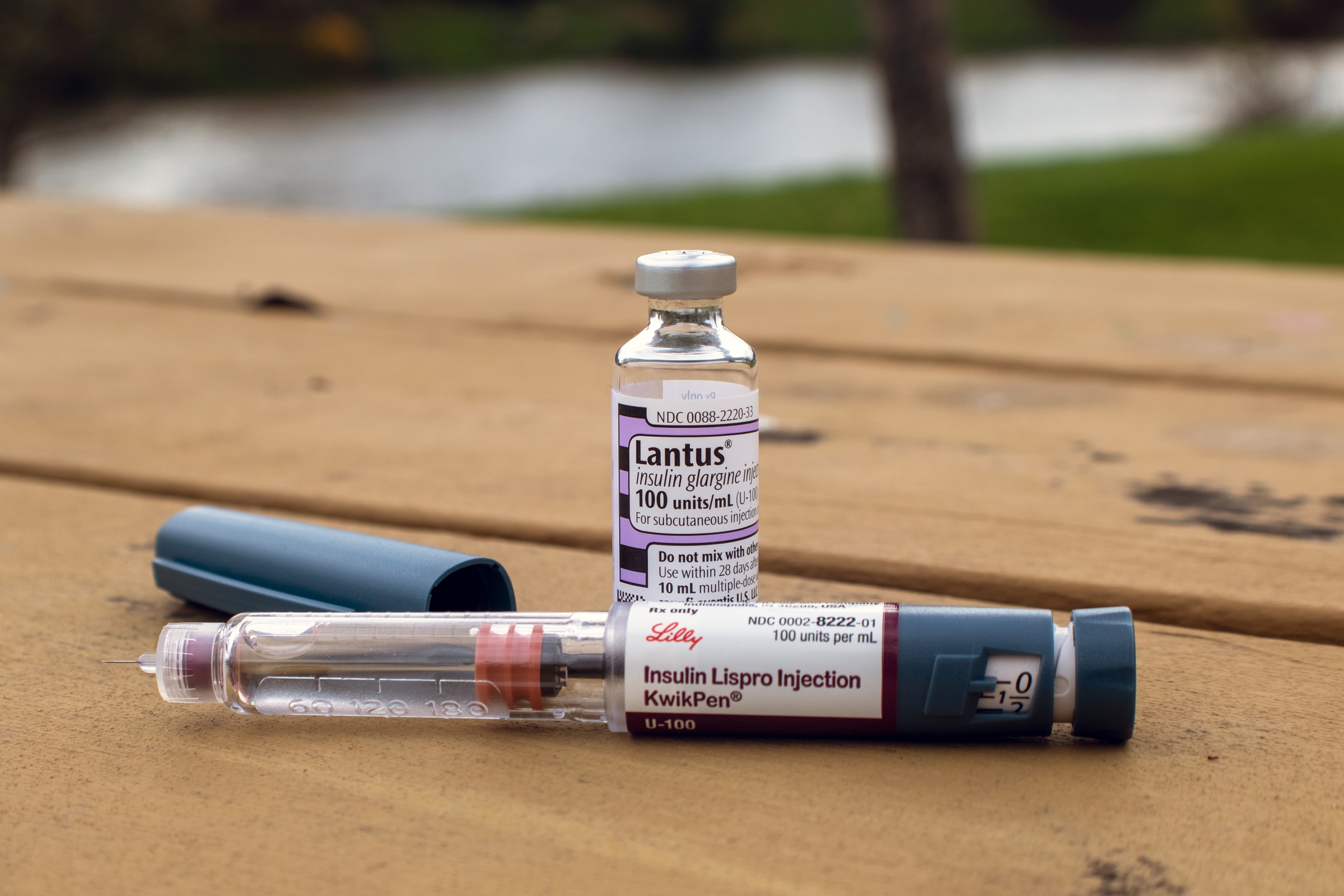 A closed bottle of insulin sitting beside an opened insulin injection