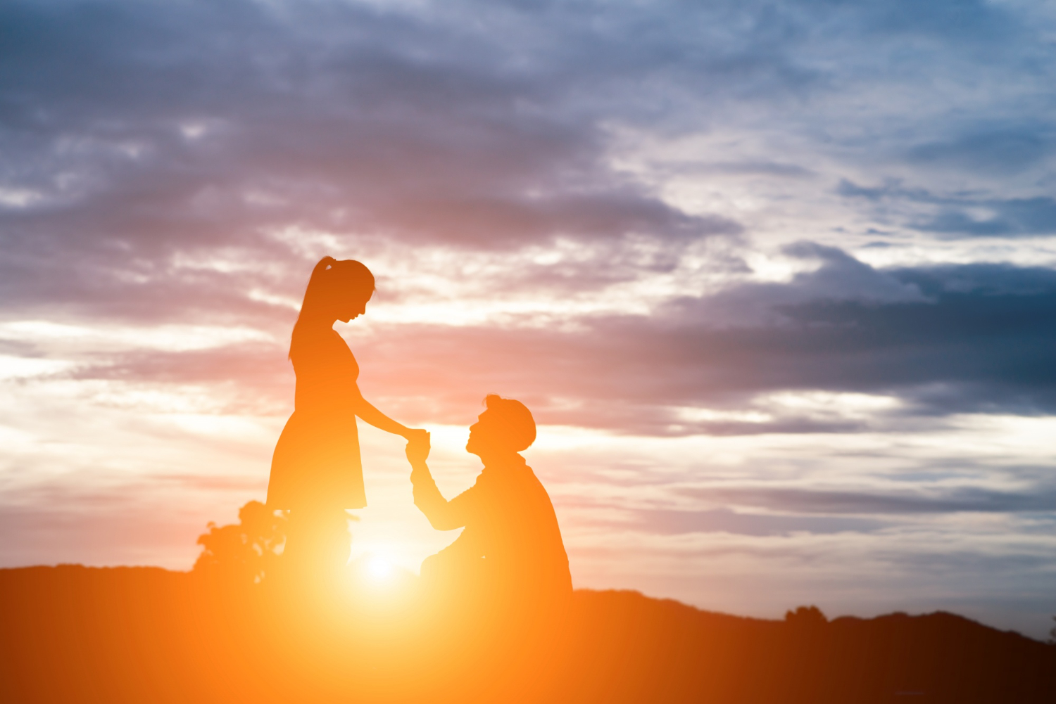 A man is proposing to a woman while the sun is rising