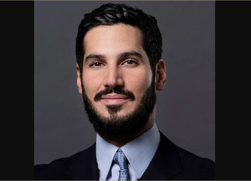 Hassan Jameel wearing a black suit on a shirt and tie
