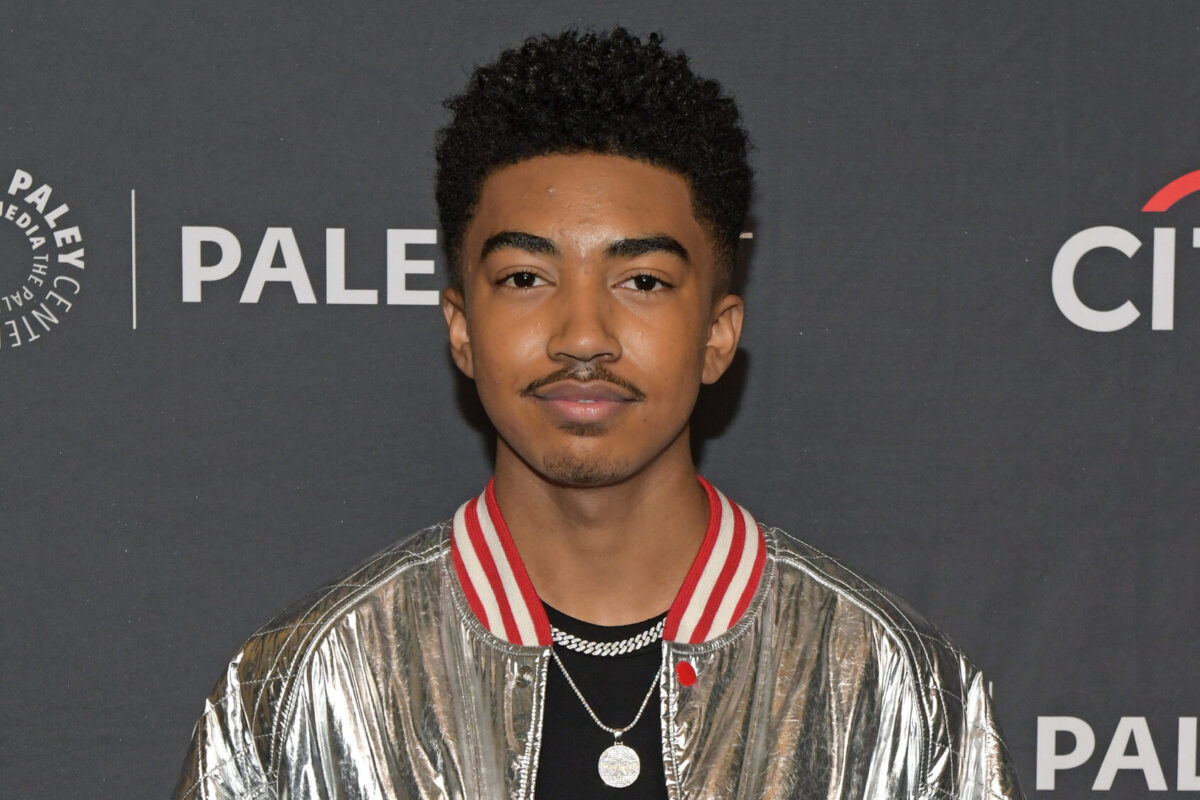 Miles Brown wearing a silver colored jacket on a black t-shirt at an event