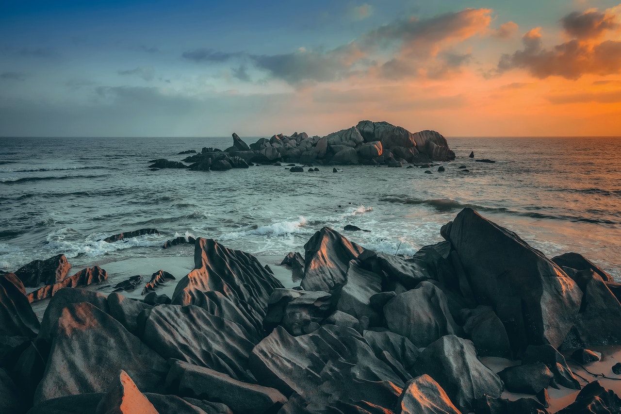Rough Rocks In The Coast Of Wavy Sea At Sunset