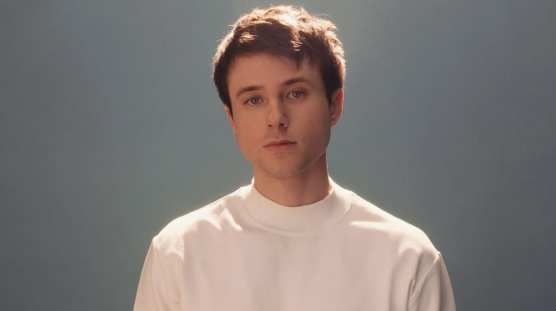 Alec Benjamin wearing a white t-shirt with a straight face