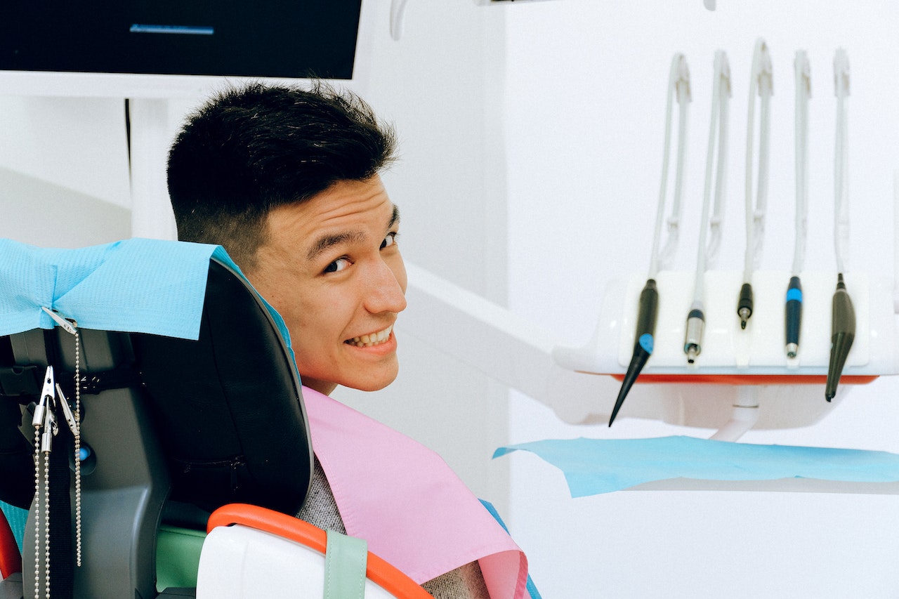 Cheerful ethnic man sitting in dental chair in modern dentist office