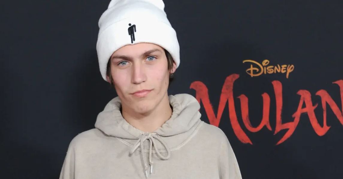 Chase Hudson wearing a white hoodie and head warmer at an event