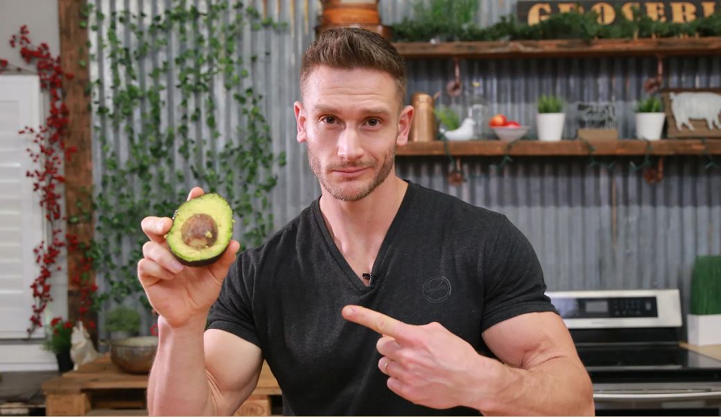 Thomas Delauer wearing a black t-shirt while holding an avocado