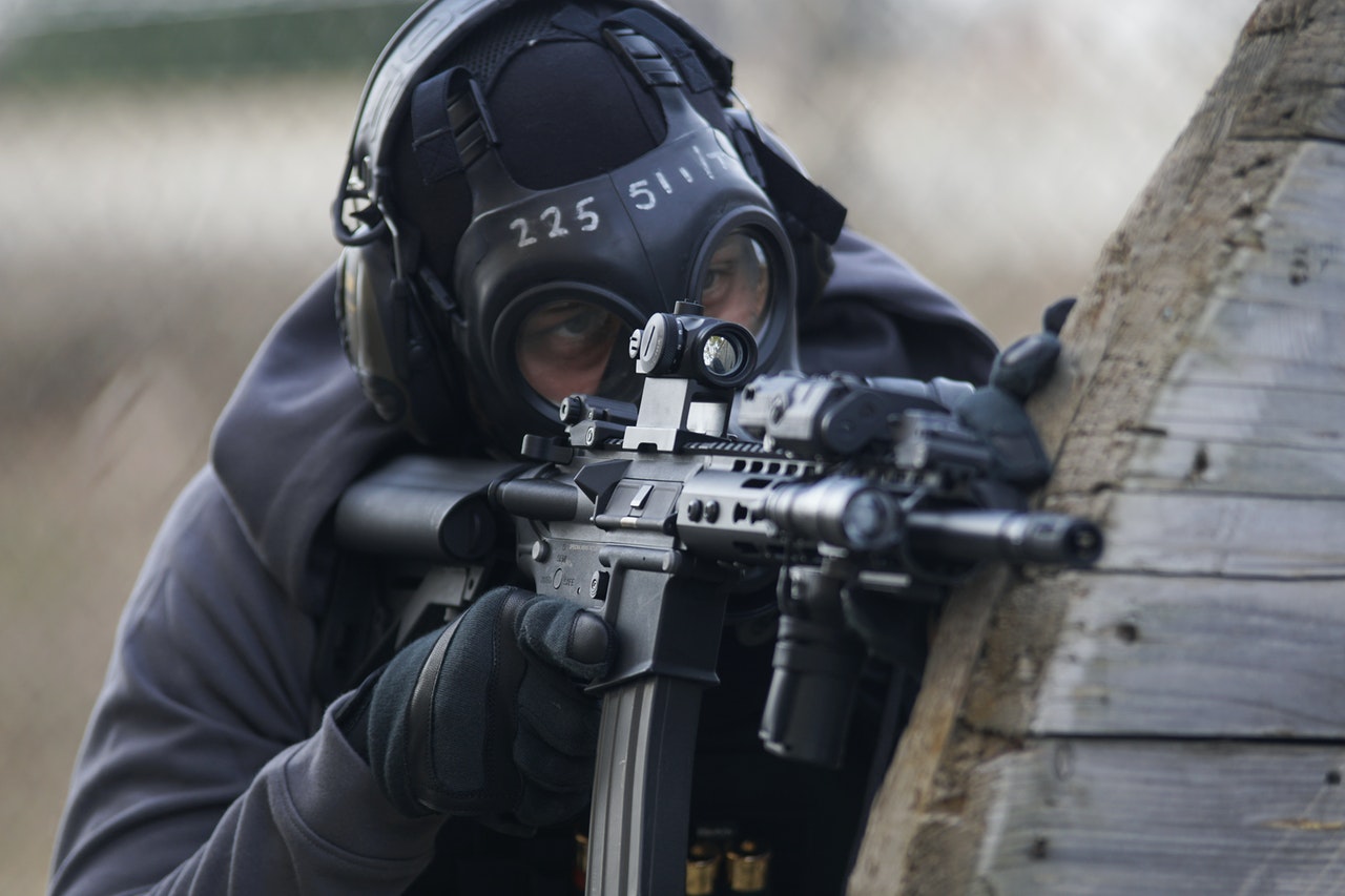 A Man Holding An Airsoft Gun in Shallow With Protective Gears