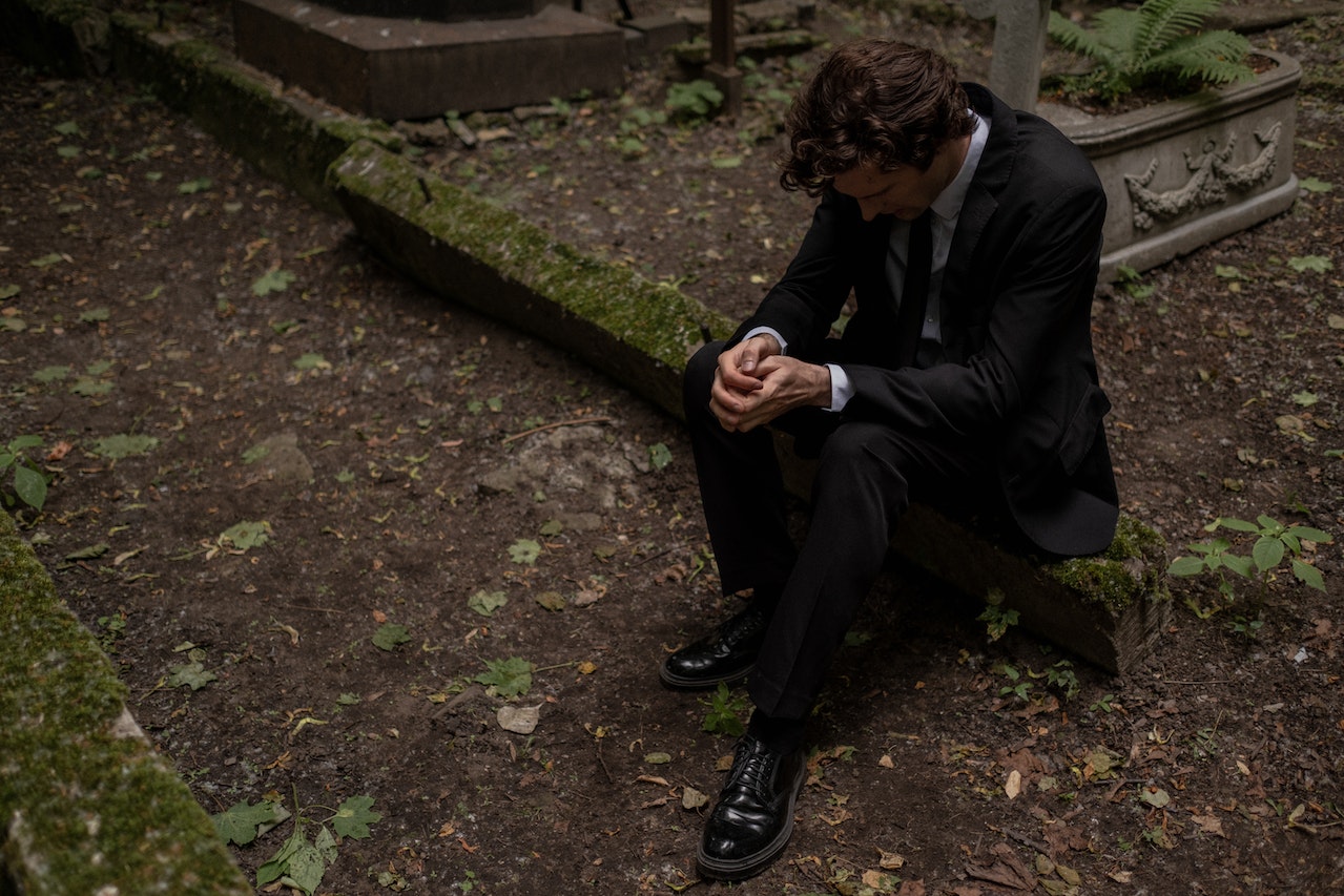 A Man in Black Suit Sitting on the Ground