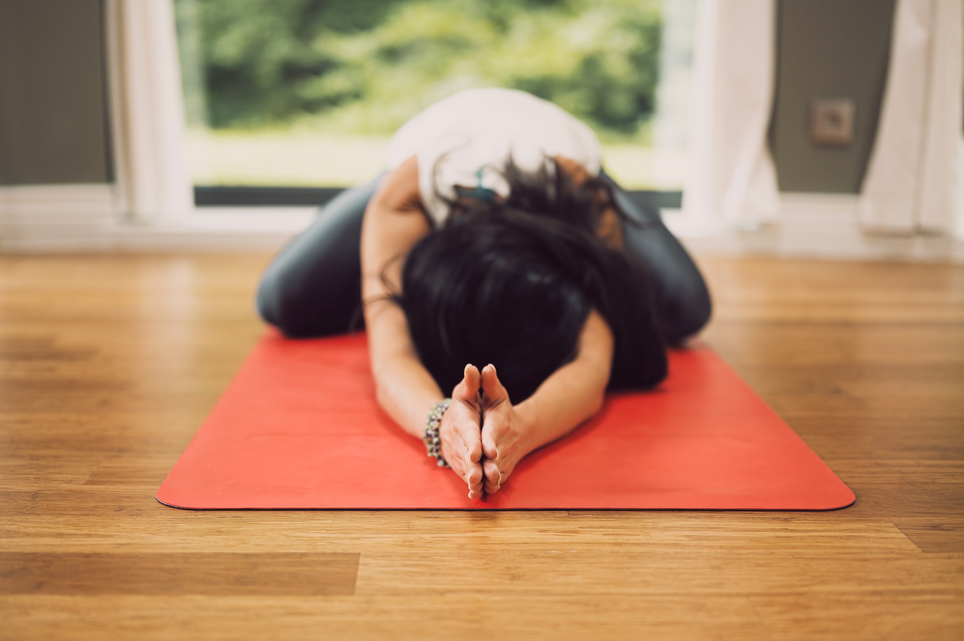 A woman doing a child yoga pose on a red yoga mat