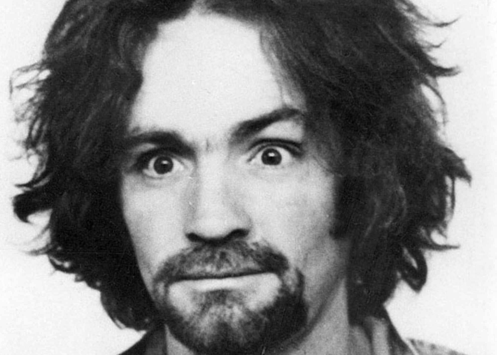 A grayscale picture of Charles Manson with his eyes wide open