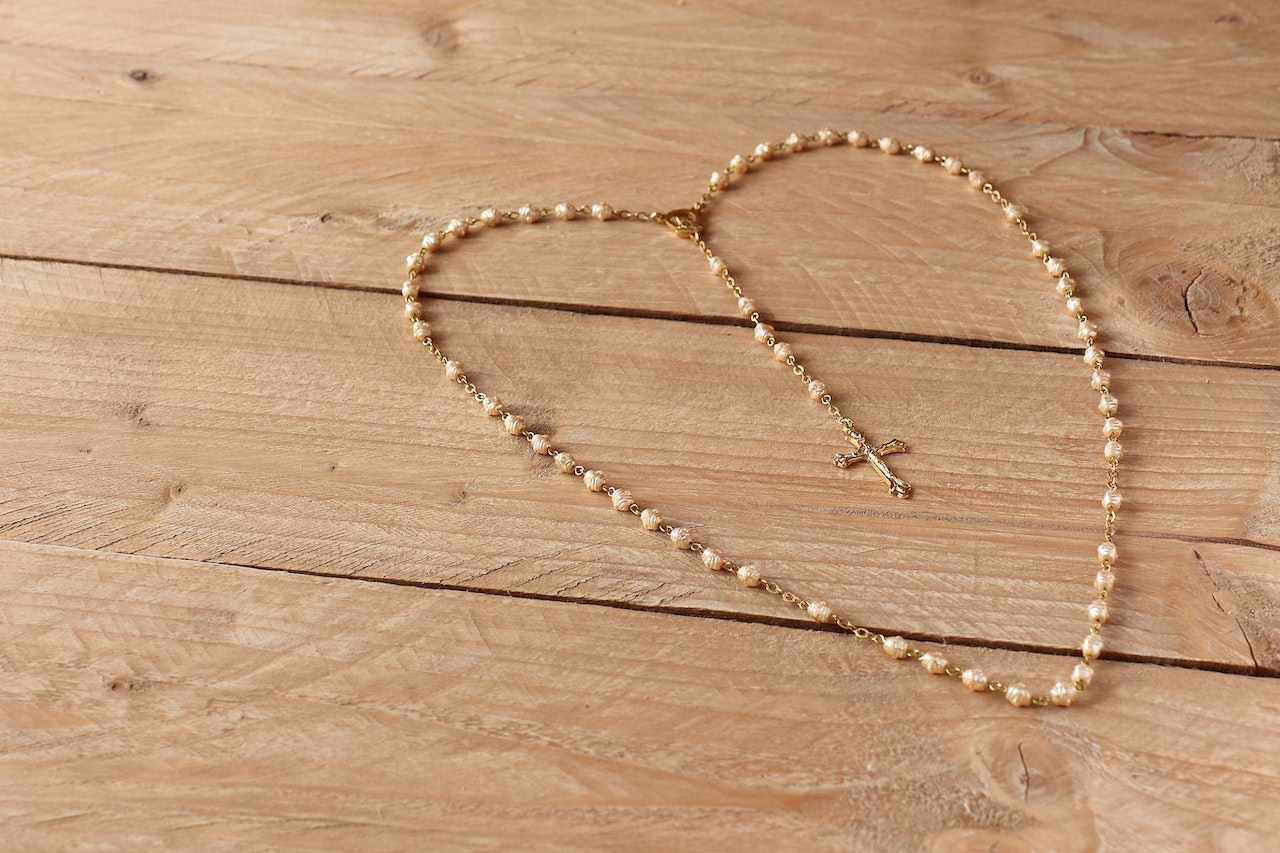 White Rosary on Beige Wooden Surface