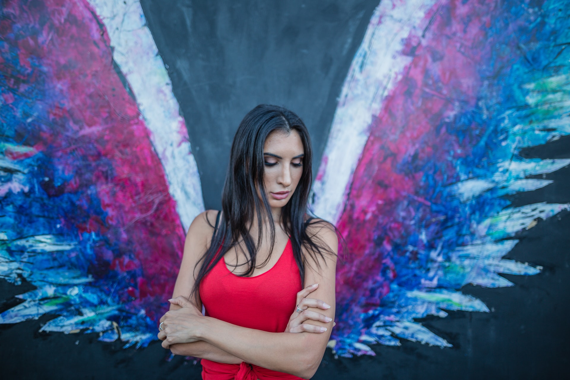 A Woman in Red Skirt Standing Against A Wall With Angel Wings