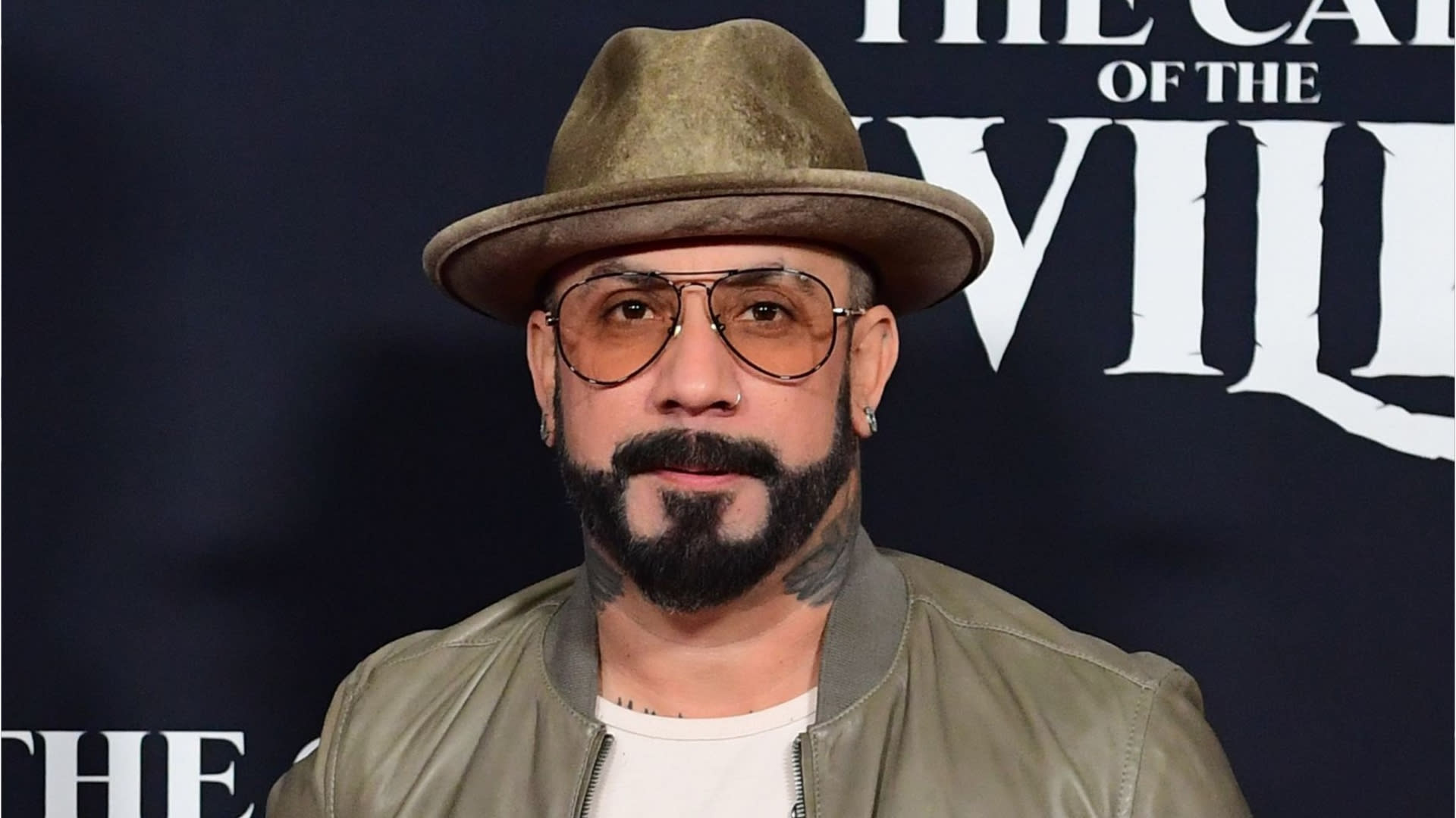 AJ McLean wearing a green jacket and green fedora hat