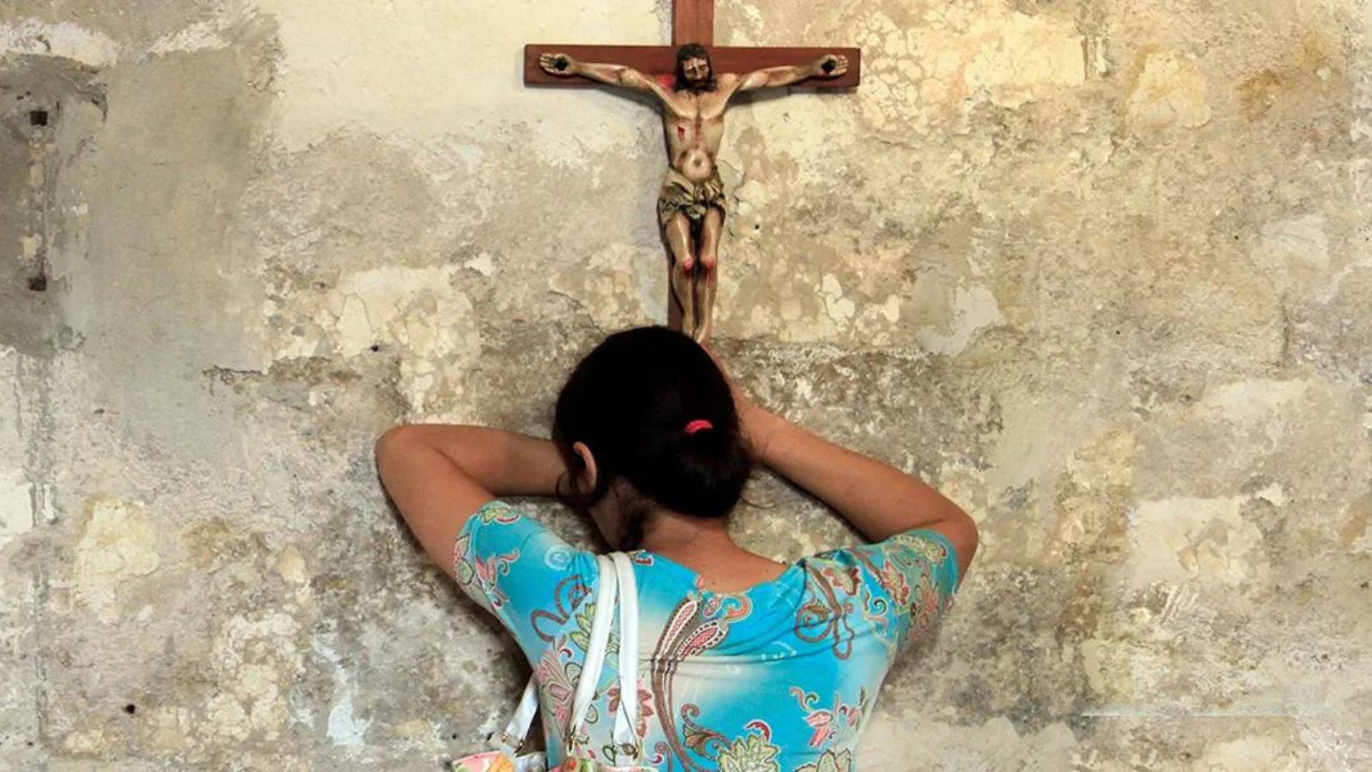 A Woman Crying And Praying In Front Of A Jesus Cross