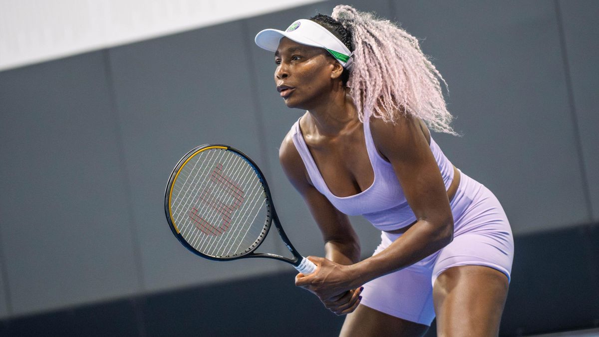 Venus Williams wearing a purple sports outfit while holding a tennis racket