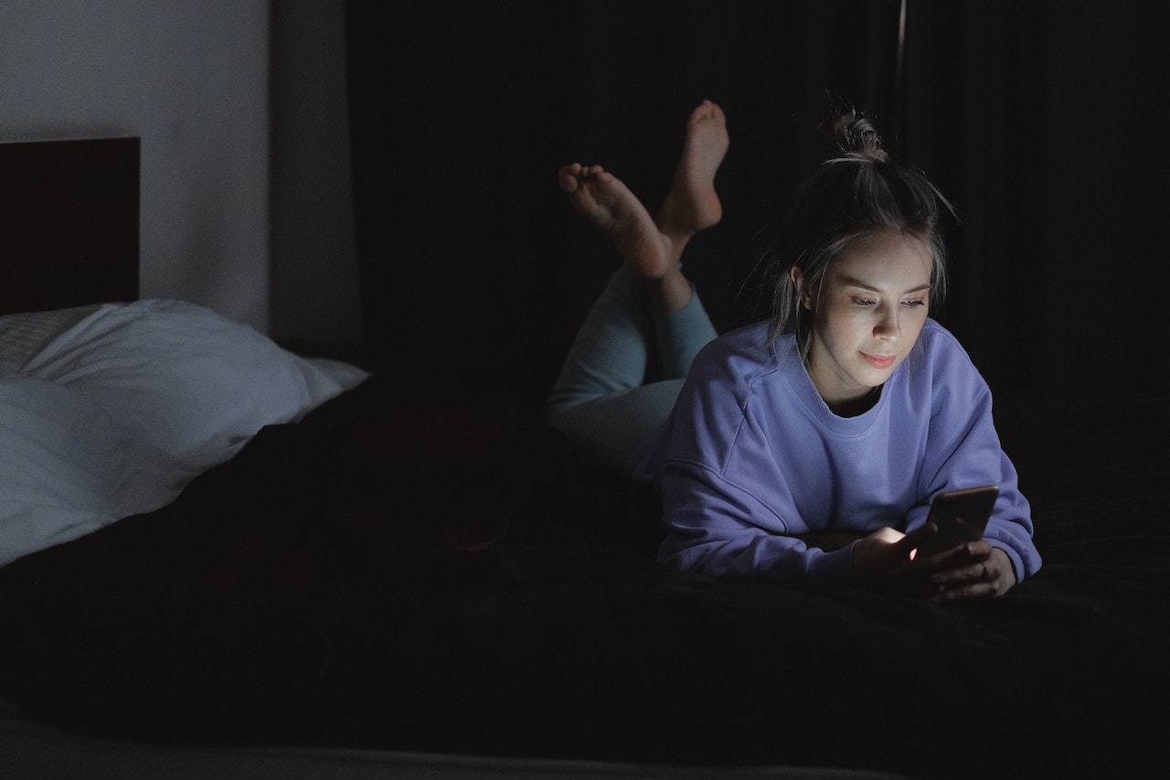 Woman Lying on Bed while Using a Cellphone