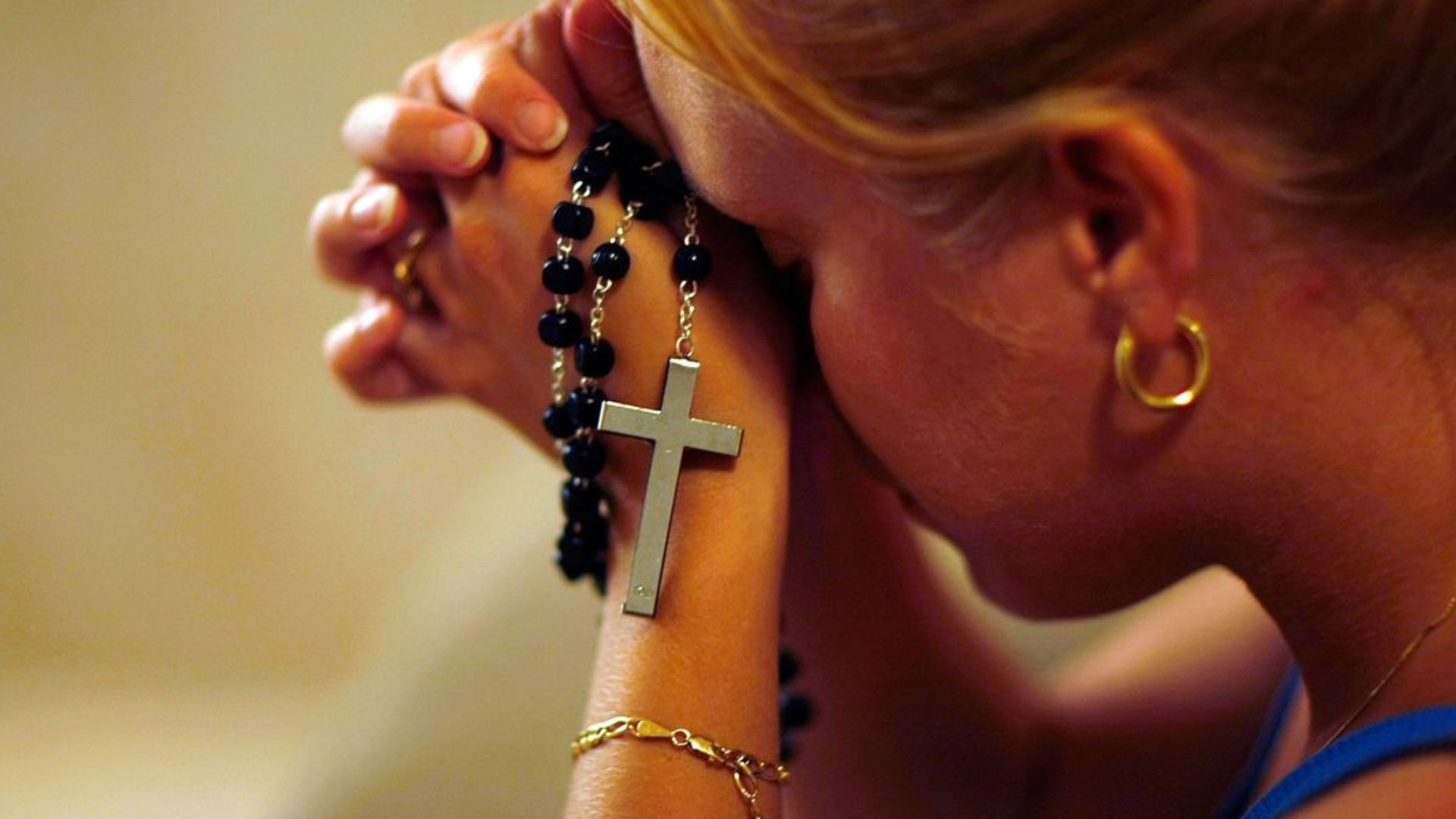 A Woman Praying While Holding Cross Necklace
