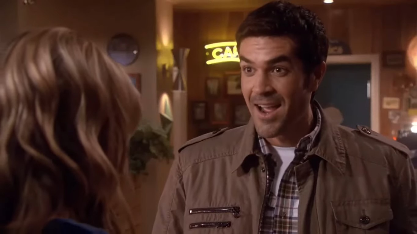 A delightedly surprised Jeff Pangman in brown jacket in a scene opposite a woman in ‘Eureka’