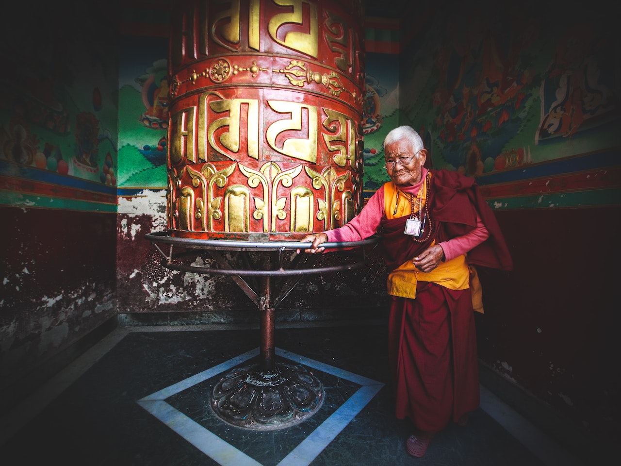 Mature Monk Walking Around Prayer Wheel in Temple