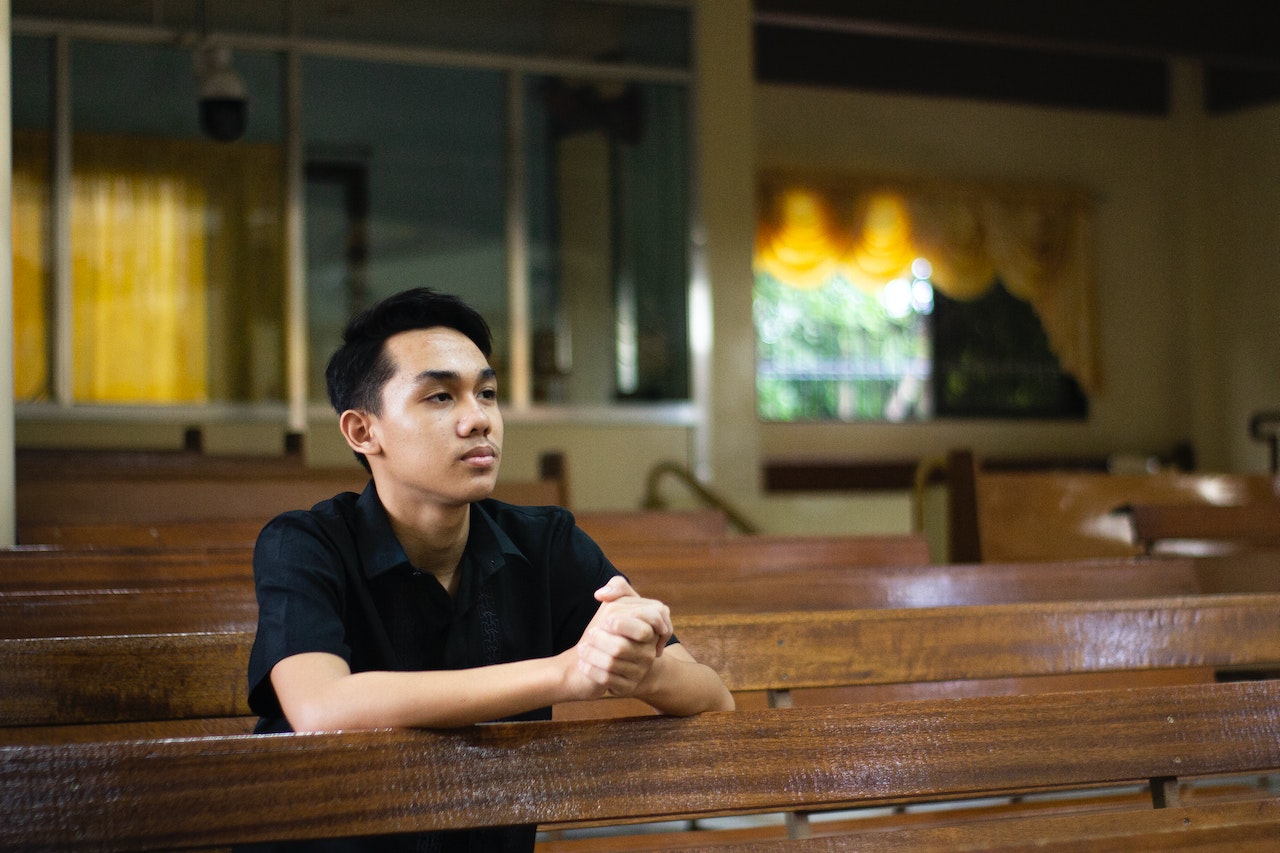 Man in Black Shirt Sitting in a Church praying