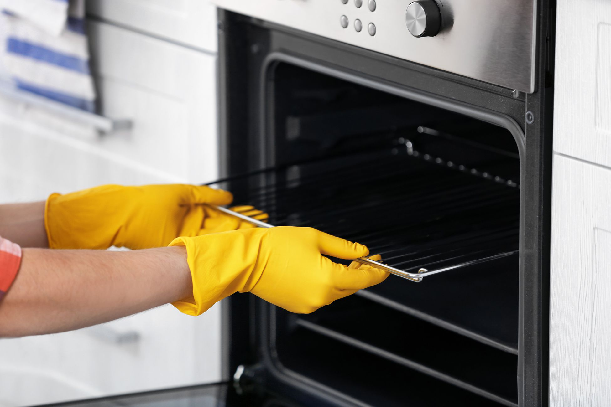 Woman Wearing Yellow Gloves Washing A Dirty Oven