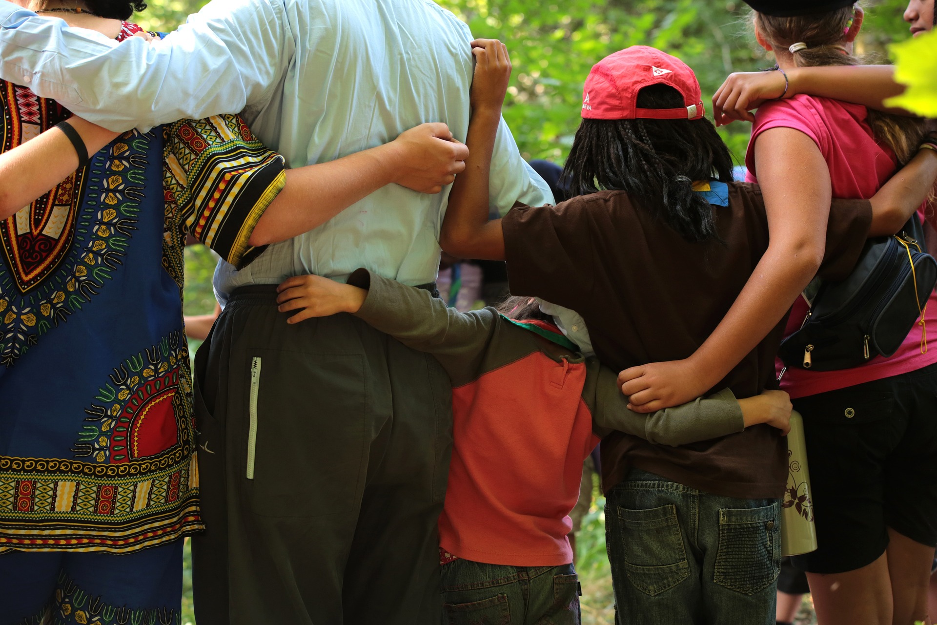 The back view of children and adults with ADHD standing near each other and hugging